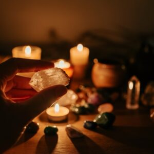 Hand met kristal en kaarslicht op de achtergrond.