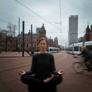 Een vrouw die mediteert in een drukke straat in Den Haag, symboliserend innerlijke rust en balans te midden van stedelijke dynamiek.