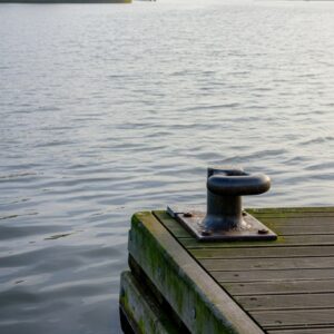 Close-up van een houten steiger met meerpaal aan de Ringvaart, zachte rimpelingen en luchtreflectie; rustgevend beeld voor Reiki nabij de Toolenburgerplas