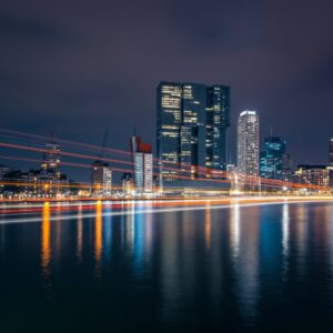 Afbeelding van de skyline van Rotterdam bij nacht, met reflecties en licht, symbool voor stedelijke energie en vitaliteit.