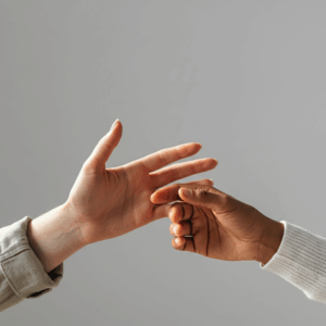 Close-up van handen die elkaar zachtjes aanraken, symbool voor verbinding en bewustwording in een professionele sfeer.