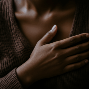 Een gedetailleerde close-up van een hand die op de borst rust, symbool voor zelfbewustzijn en verbinding met eigen gevoelens.