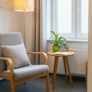 Een uitnodigende therapieruimte in Schoonhoven, met een comfortabele fauteuil, een klein tafeltje met een plant en notitieboekje, en een raam met zacht natuurlijk licht.