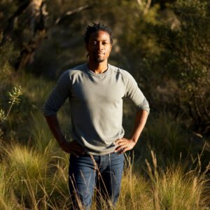 Afbeelding van een zelfverzekerde man in een natuurlijke omgeving, symbool voor lichaamsbewustzijn en zelfbewustzijn.